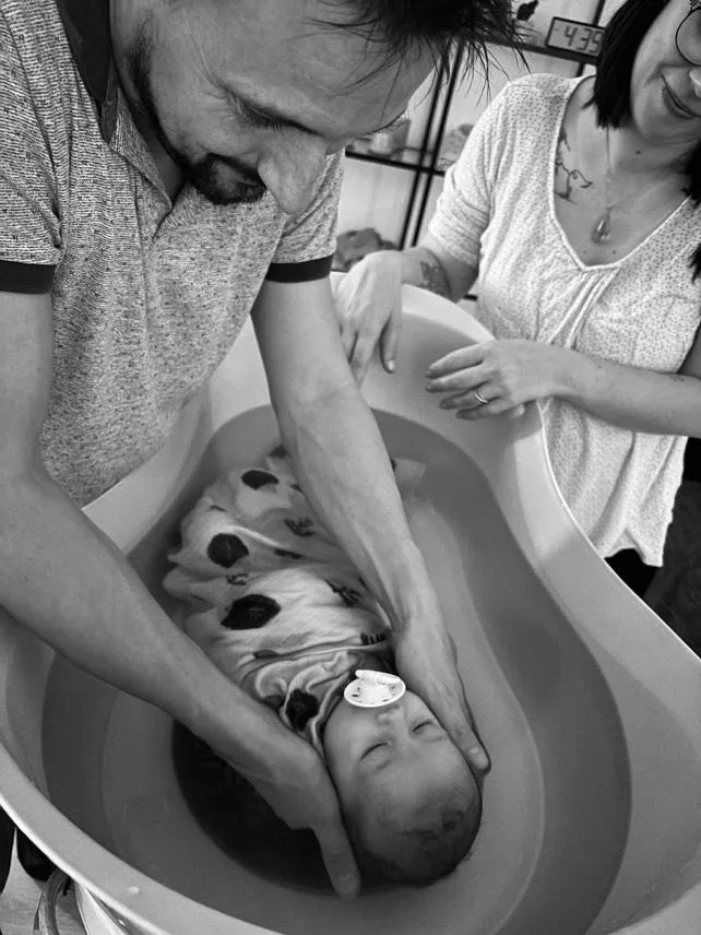 Parent baignant son bébé lors du rituel du bain sensoriel